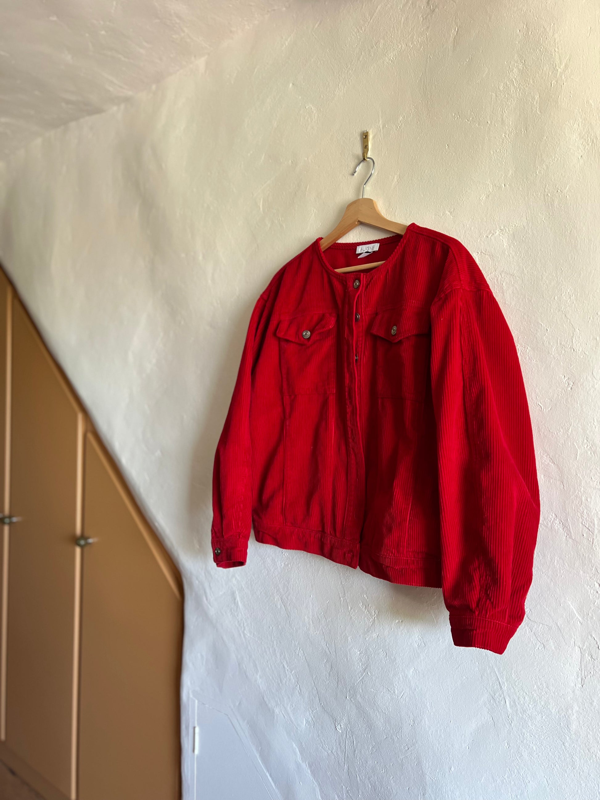 Aligne Red Cord Moto Jacket hanging against a white wall 