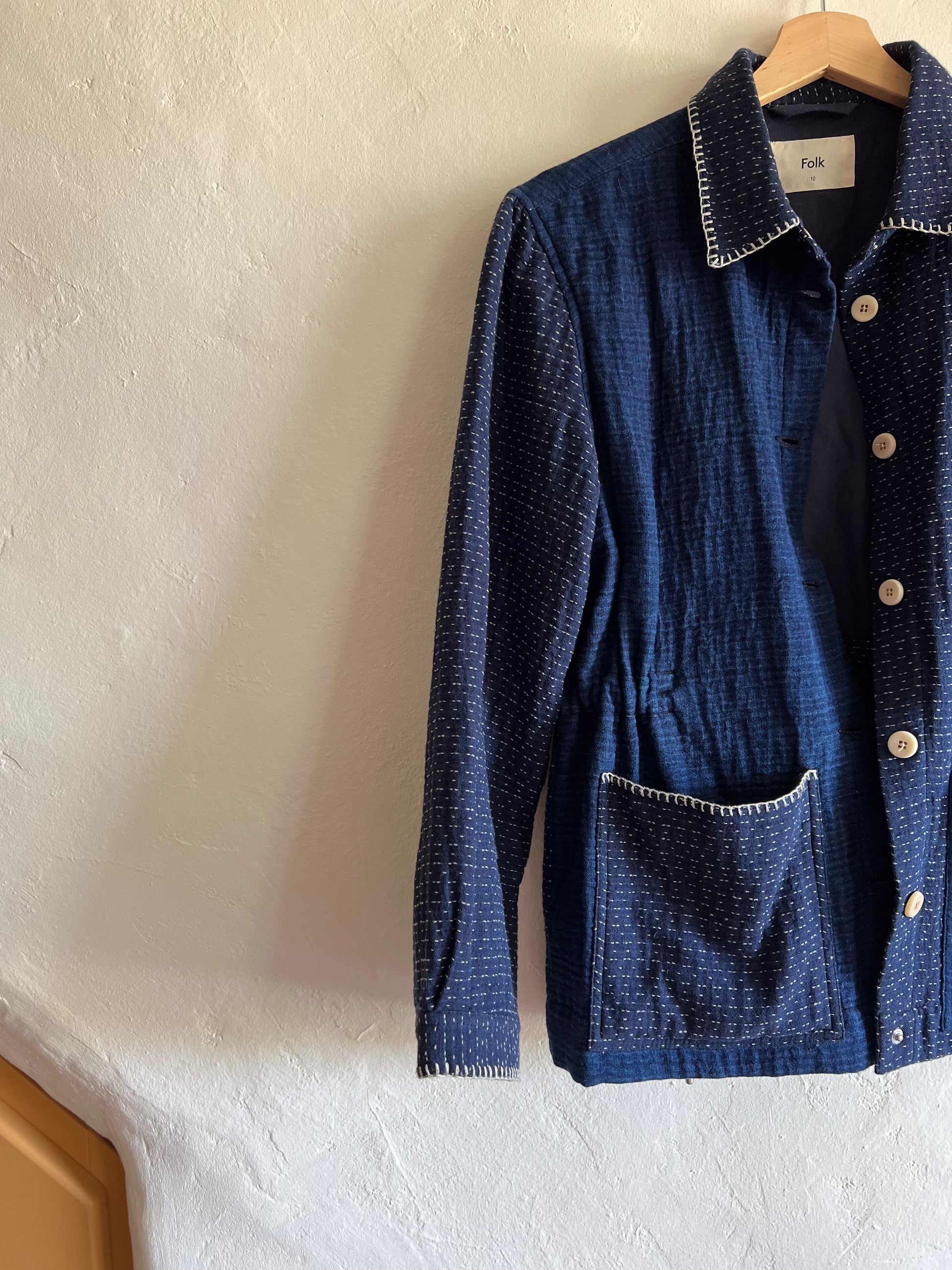 Folk Indigo Sashiko Waffle Patch Jacket hung against a white wall 