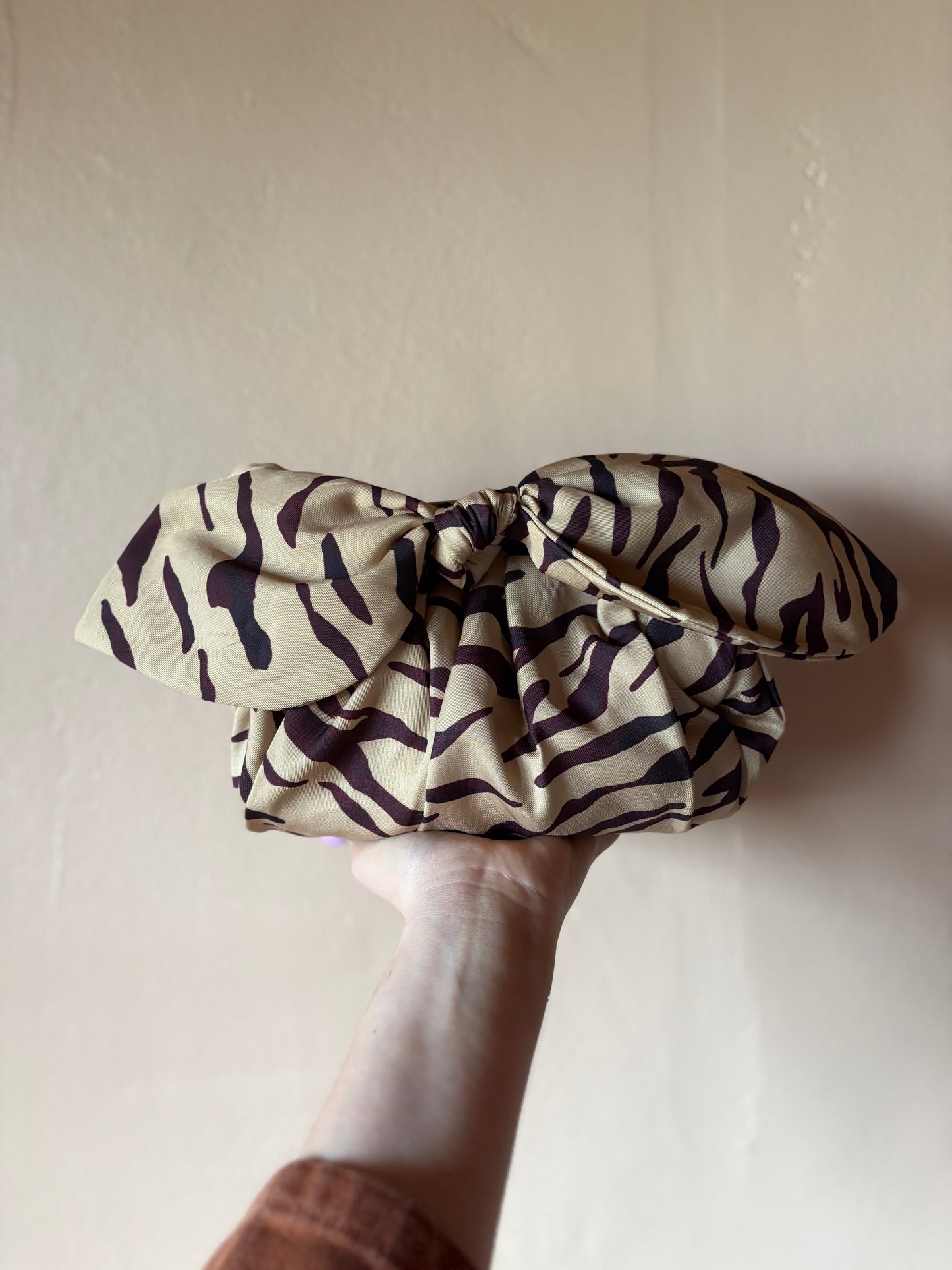 Zebra-patterned scrunchie held by a hand against a plain background