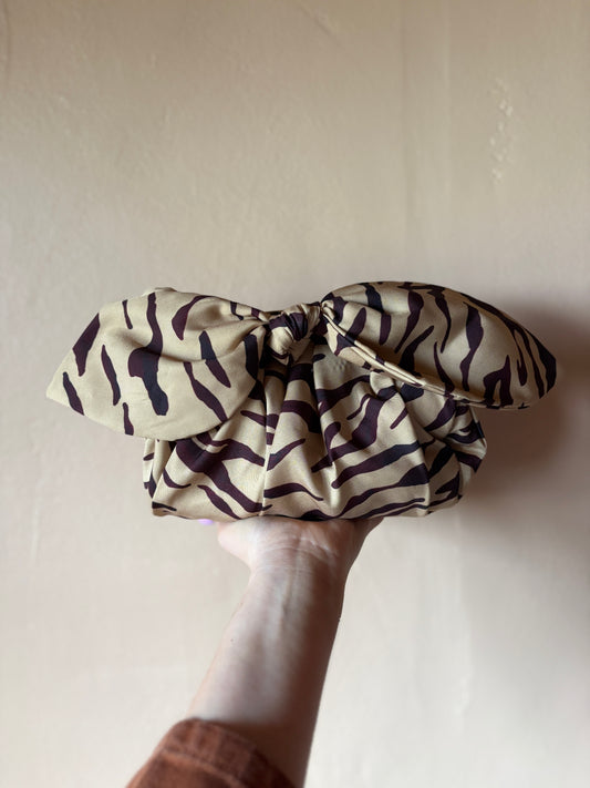Zebra-patterned scrunchie held by a hand against a plain background