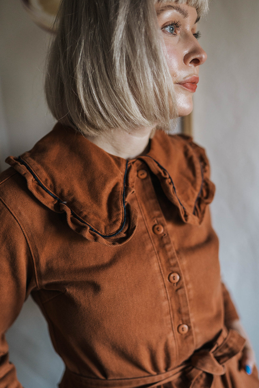 The Tiny Big Sister Rust Oversize Ruffle Collar Jumpsuit worn on model 