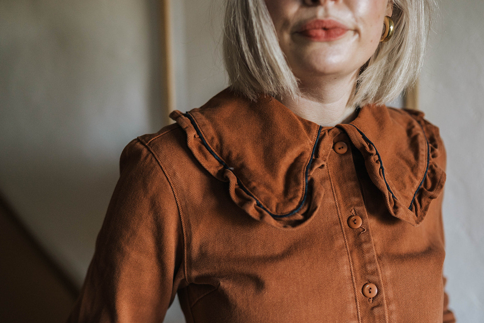 The Tiny Big Sister Rust Oversize Ruffle Collar Jumpsuit worn on model 